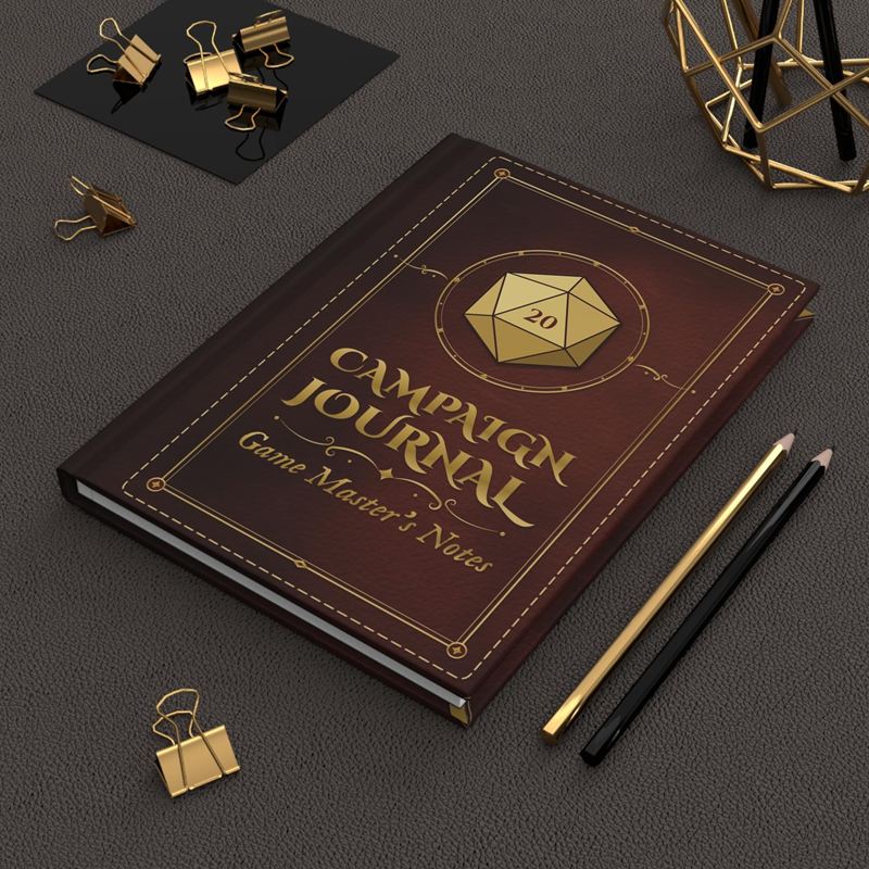 Oxblood leather-look hardcover journal with a gold D20 and the words Campaign Journal, beside gold and black pencils
